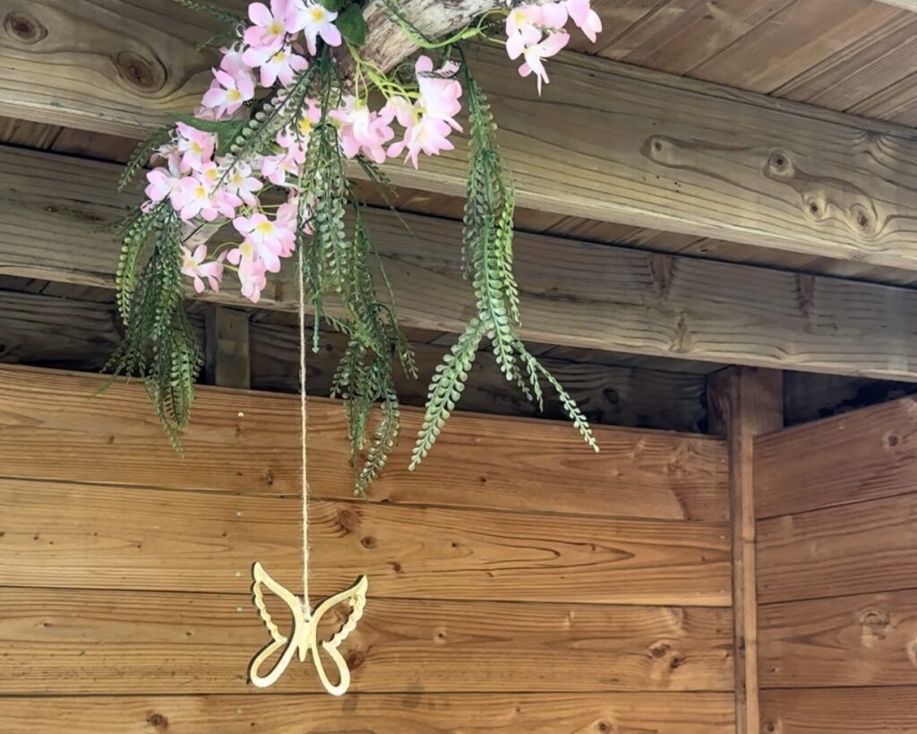 Diy zomertak zelf maken met kunstbloemen en bladeren hangt er ornamenten aan.